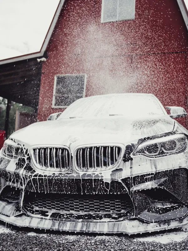 Black BMW M2 covered in foam during a hand wash